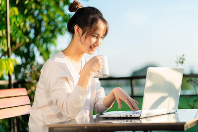 Businesswoman using laptop while sitting at park
