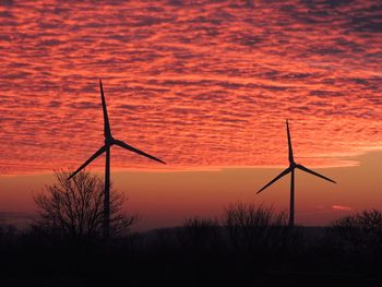 Windmills against sky during sunset