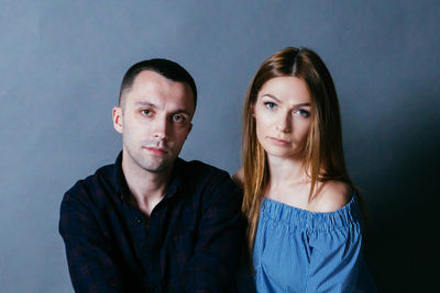 Portrait of couple sitting against gray background