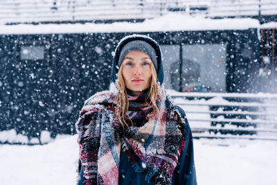 Portrait of a young caucasian woman in a hood in a snowstorm.