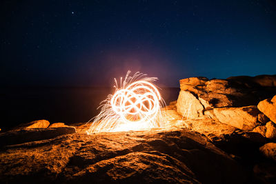 Low angle view of bonfire on rock against sky at night