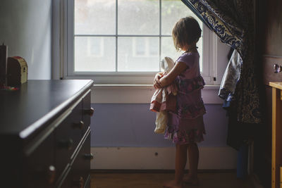 Girl looking through window at home