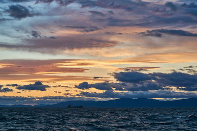 Scenic view of sea against dramatic sky during sunset