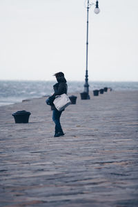 Side view of woman on beach against sky