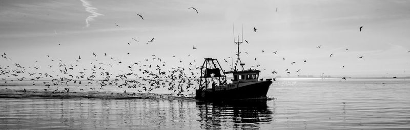 Silhouette man flying over sea against sky