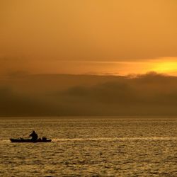 Boat sailing in sea at sunset