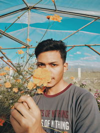 Portrait of young man holding flower