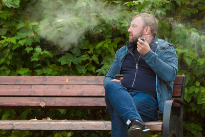 Man smoking pipe while sitting on bench