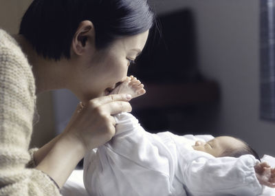 Close-up of mother with newborn son on bed at home