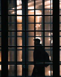 Silhouette man seen through glass window