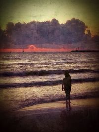 Woman standing on beach at sunset