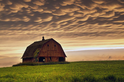Abandoned house on field against sky during sunset