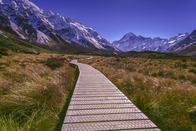 Empty boardwalk against snowcapped mountains