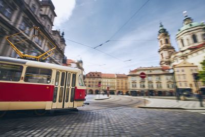 Train on street amidst buildings in city