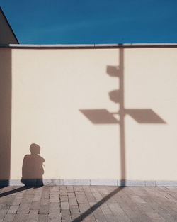 Shadow of woman on wall against sky