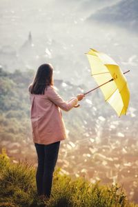 Woman holding umbrella against mountain