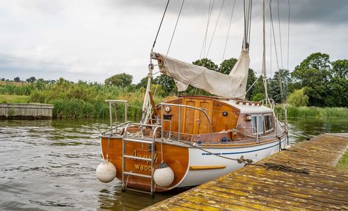 Sailboats moored on lake against sky