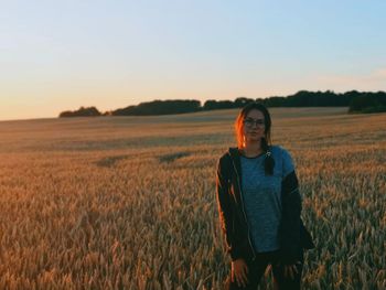 Portrait of woman standing on land against clear sky during sunset