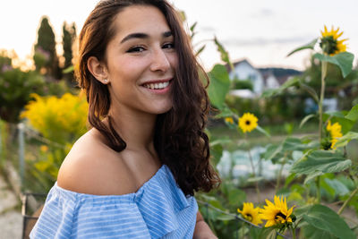 Portrait of smiling young woman against plants