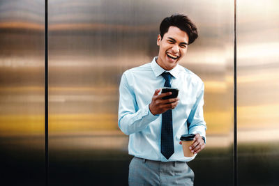 Portrait of smiling young man using mobile phone at office