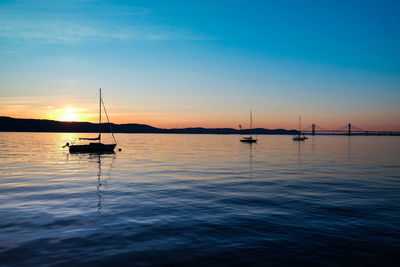 Silhouette sailboats in sea against sky during sunset