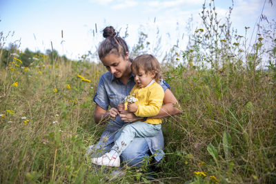 Mother with daughter sitting in field