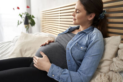 Pregnant woman resting on bed at home