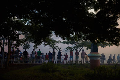 People by trees against sky