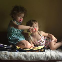 Sisters sucking pacifiers at home