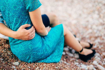 Low section of woman sitting on rock