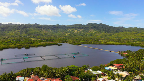 Fish farm on the background of mountains with forest and sky with clouds. 