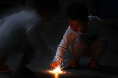 Boy holding lit sparkler at night