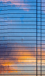 The building covers with glasses that have reflection from dusk sky and cloud on it.