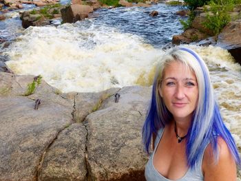 Portrait of woman with dyed hair against river