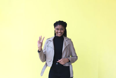 Portrait of smiling young woman against gray background