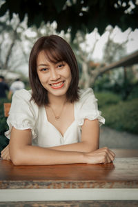 Portrait of young woman sitting on table
