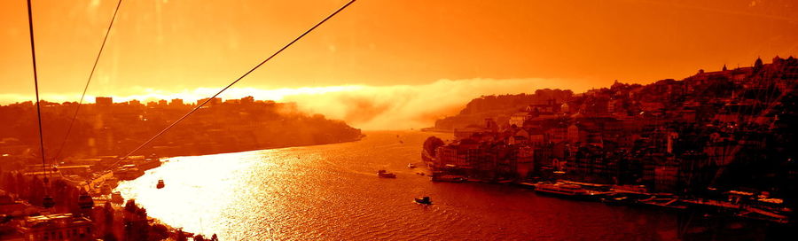 Panoramic view of river amidst buildings against sky during sunset