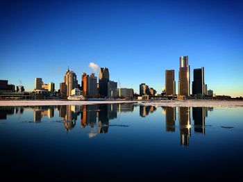 Reflection of buildings in lake against blue sky