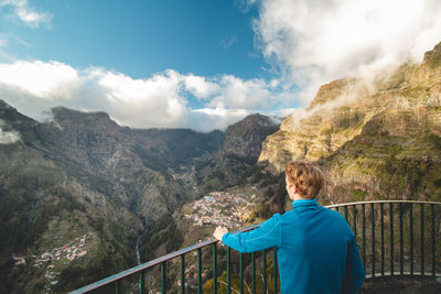 Blonde man looks out over the village of curral das freiras on the island of madeira, portugal