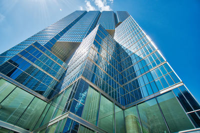 Low angle view of modern glass building against blue sky