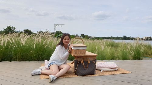 Young woman sitting on seat against sky