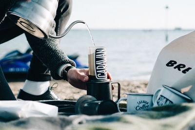 Midsection of person holding smart phone by sea