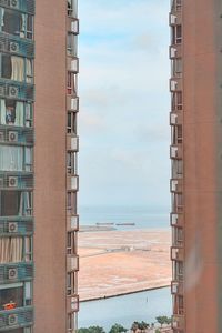 Buildings in city by beach against sky