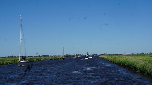 Sailboats on road against blue sky