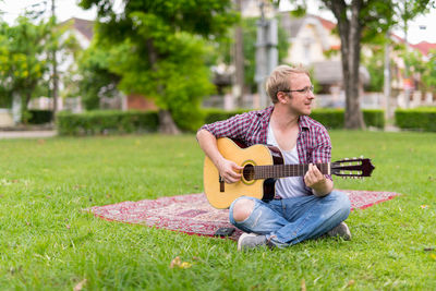 Young man playing guitar on grass
