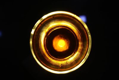 Close-up of illuminated light bulb against black background