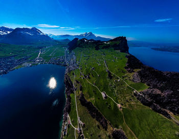 High angle view of sea and mountains against blue sky