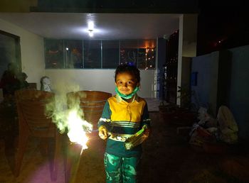 Portrait of cute boy standing in illuminated room