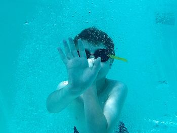 Boy showing hand while swimming in sea