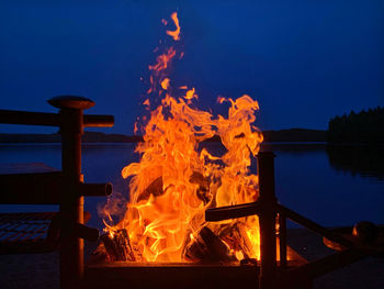 Bonfire on wooden structure in lake against sky at dusk
